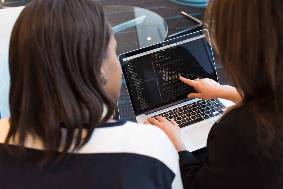 Two developers building an application together, reviewing code on a laptop