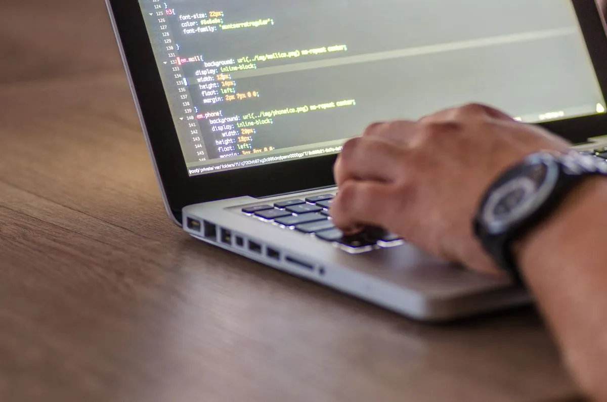 Hands writing code on a laptop